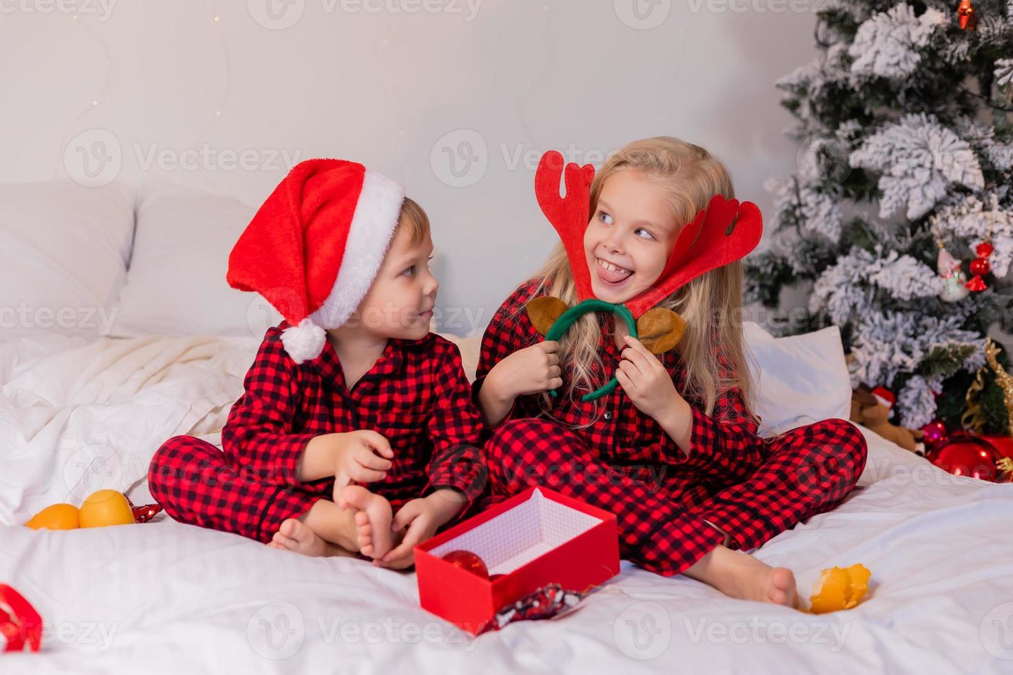 two happy children in pajamas for Christmas are sorting presents and playing with Christmas toys. High quality photo