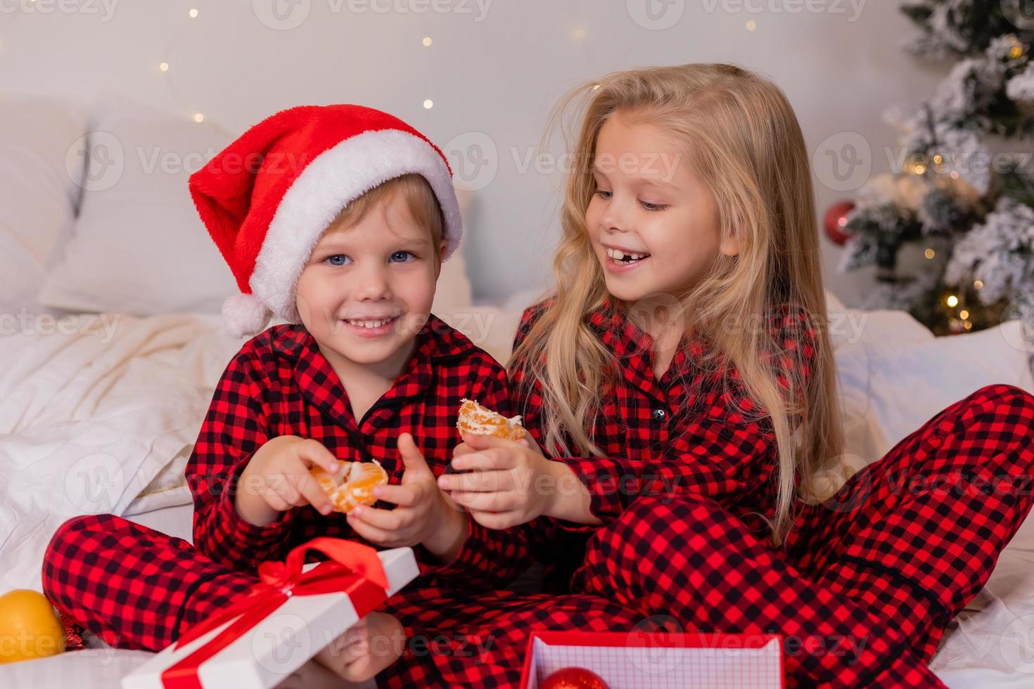 two happy children in pajamas for Christmas are sorting presents and playing with Christmas toys. High quality photo
