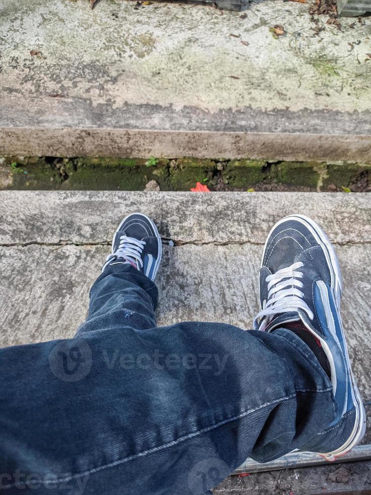 photo of a man sitting cross-legged wearing jeans and shoes
