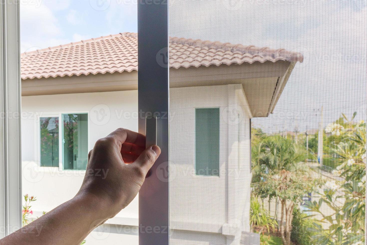 Hand hold mosquito net wire screen handle on house window photo