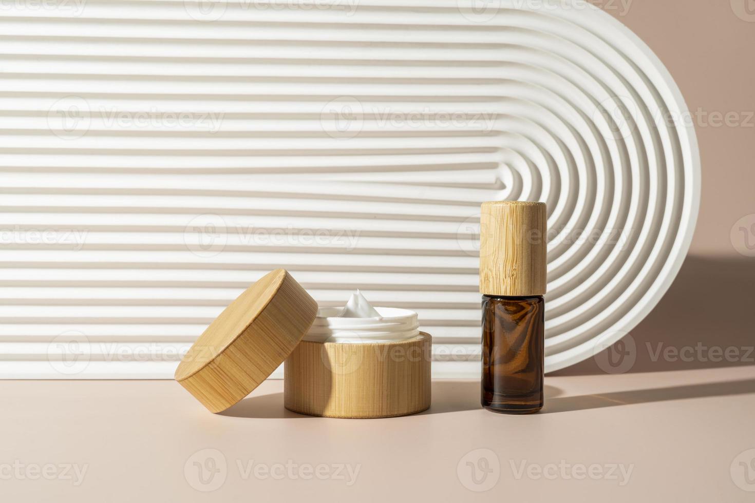 una crema facial fresca en una caja de madera y aceite esencial cerca de la bandeja de cerámica blanca. maqueta de cosméticos de marketing de productos foto