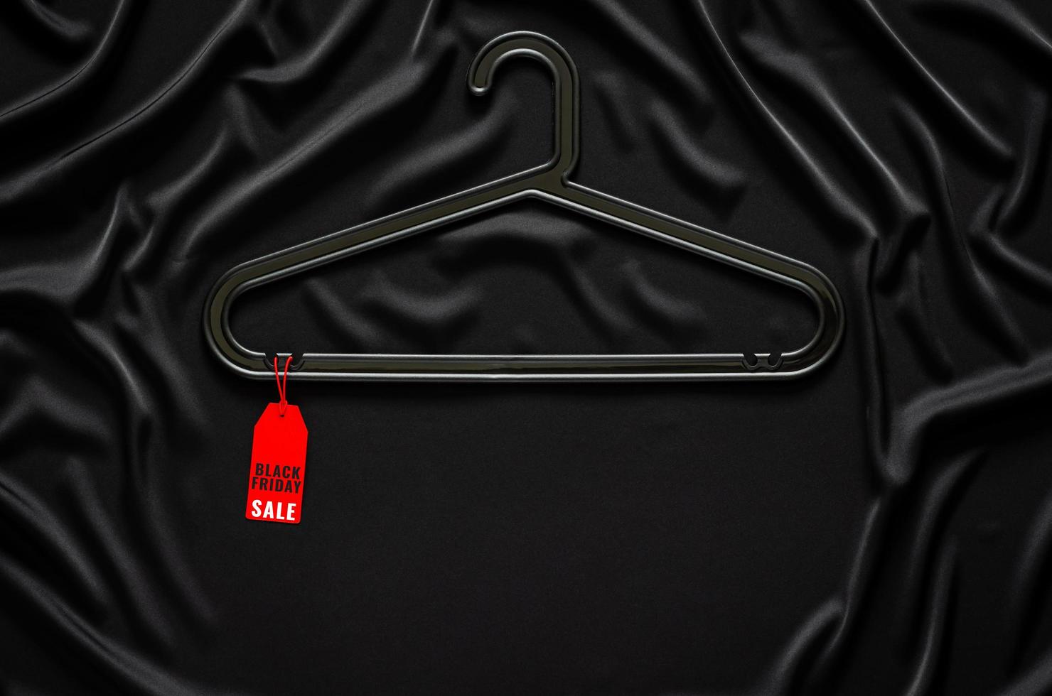 A black hanger with red price tag on black smooth and wavy cloth with space for text. Black Friday concept. photo