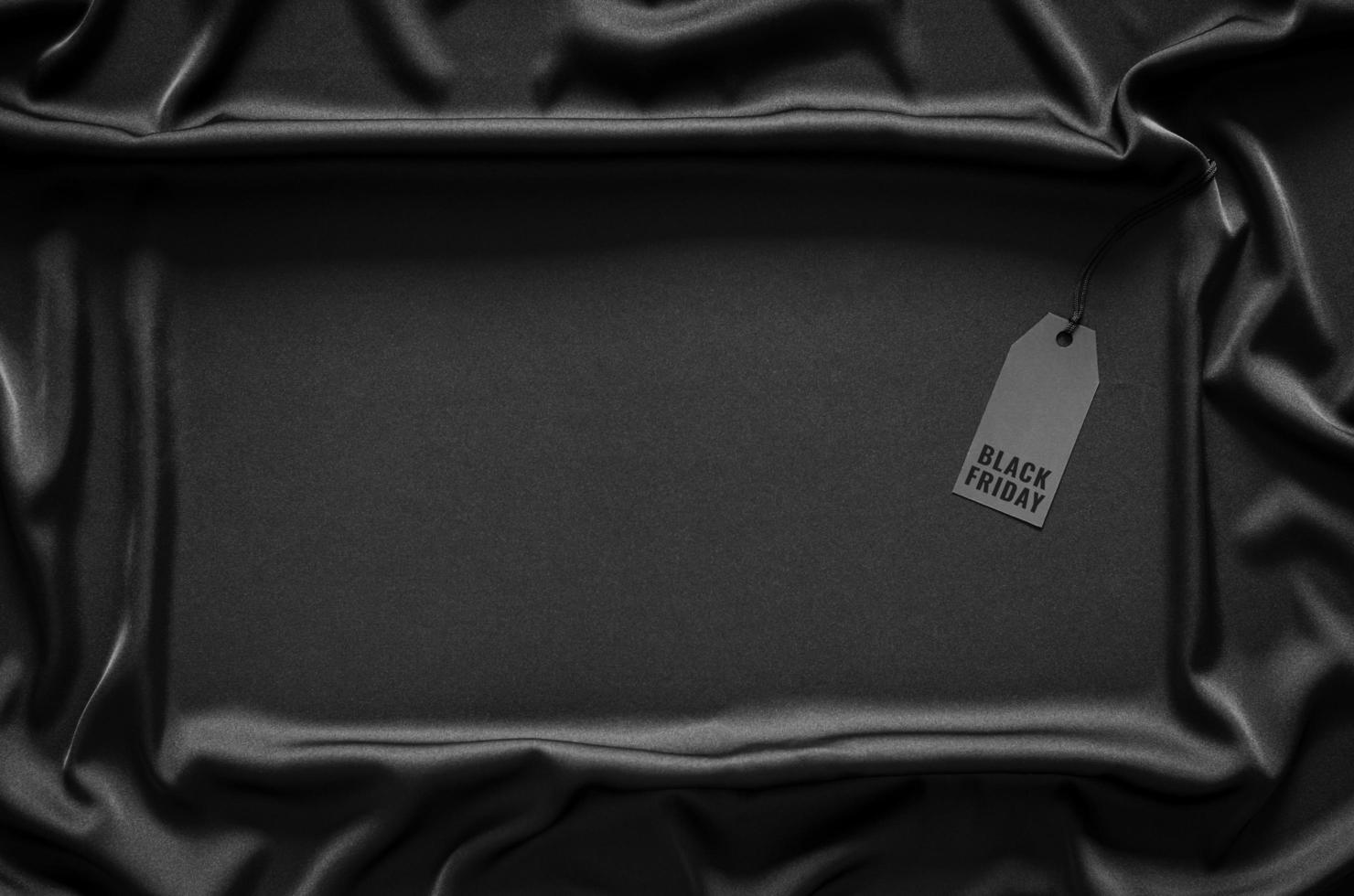 A black price tag on black smooth and wavy cloth with space for text. Black Friday concept. photo