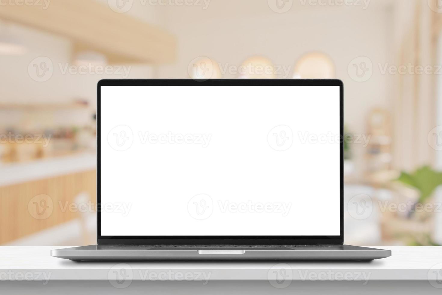 Laptop with blank screen on marble table with cafe coffee shop blur background photo