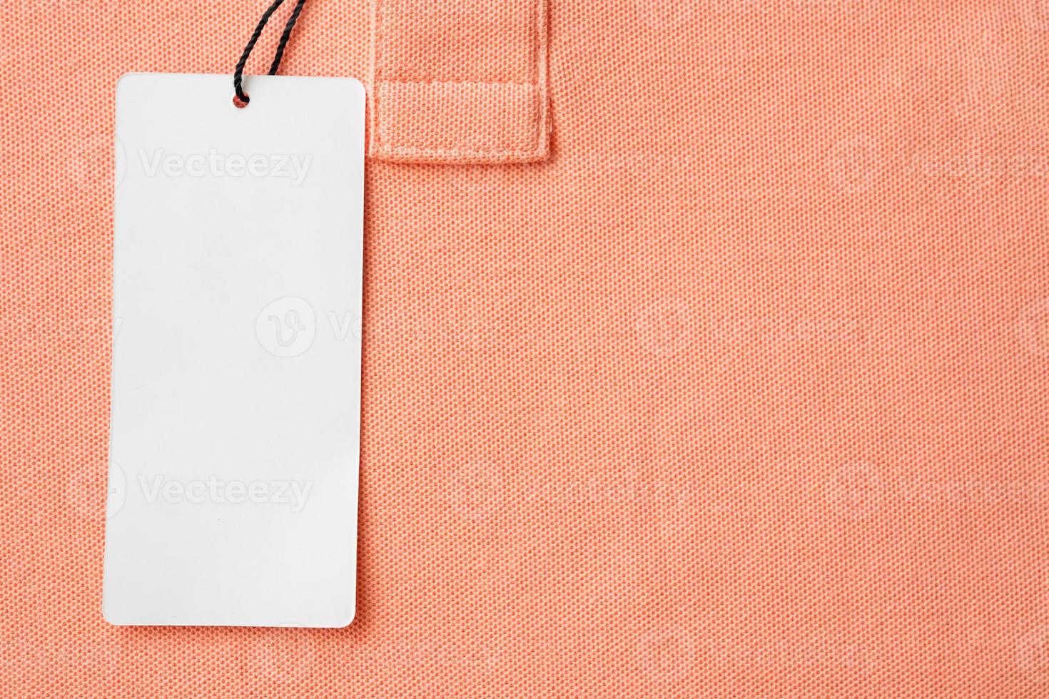 Blank white clothes tag label on pink fabric texture background photo