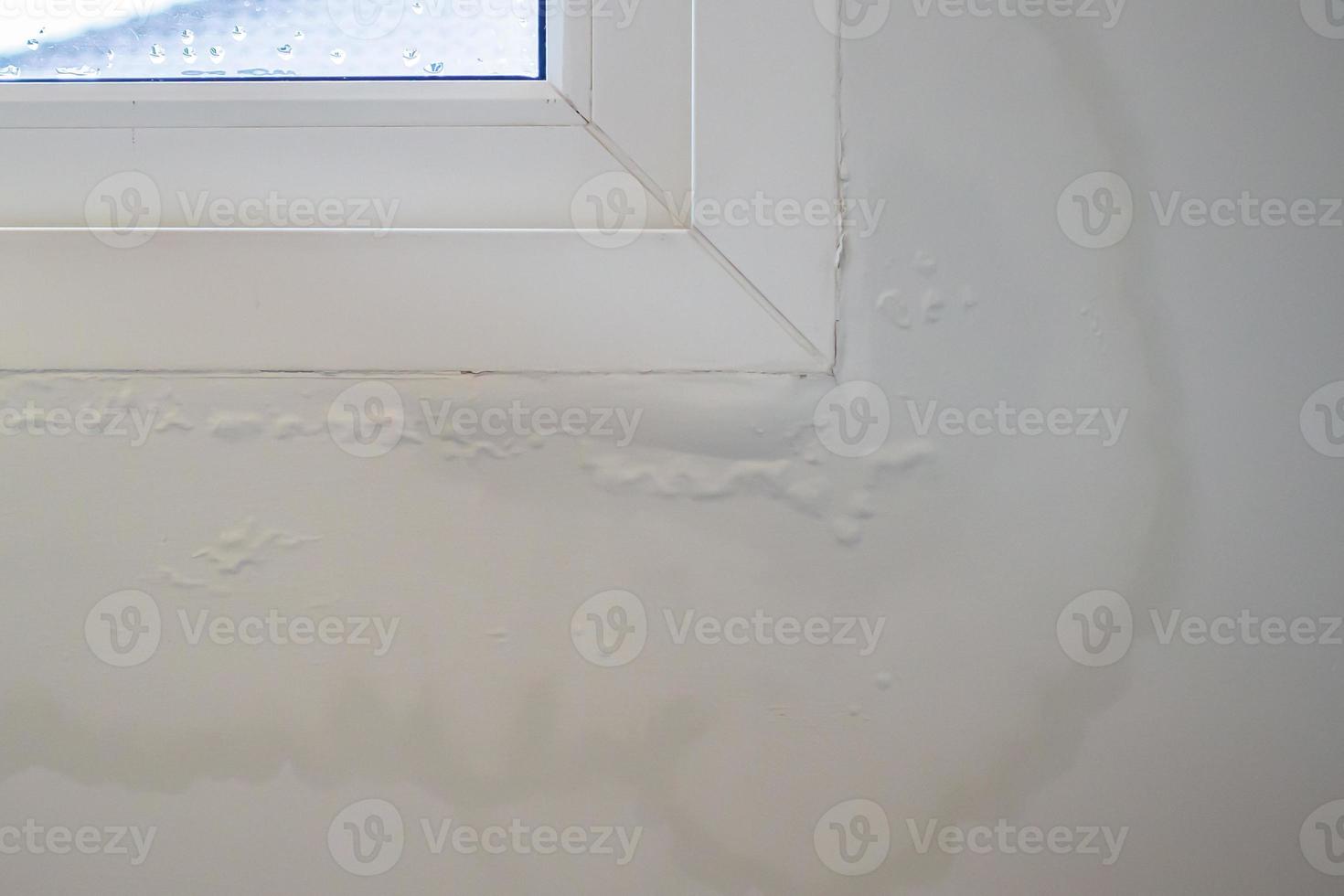 La pared de la casa cerca de la ventana con una mancha de agua muestra pintura desconchada foto