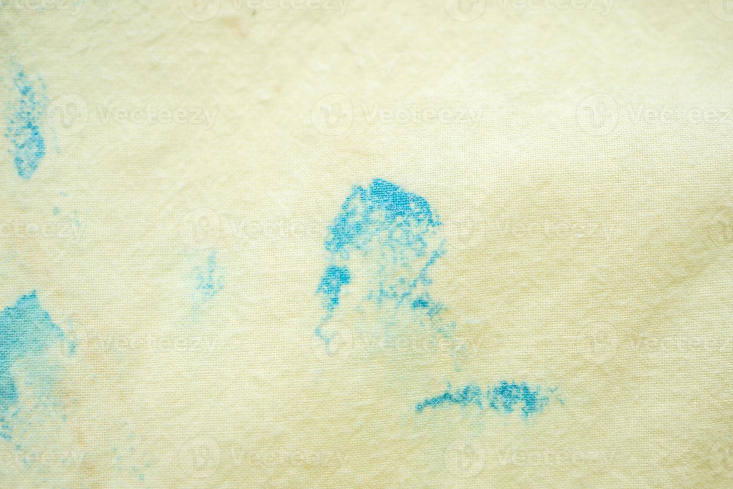 dirty color stain on yellow fabric texture background photo