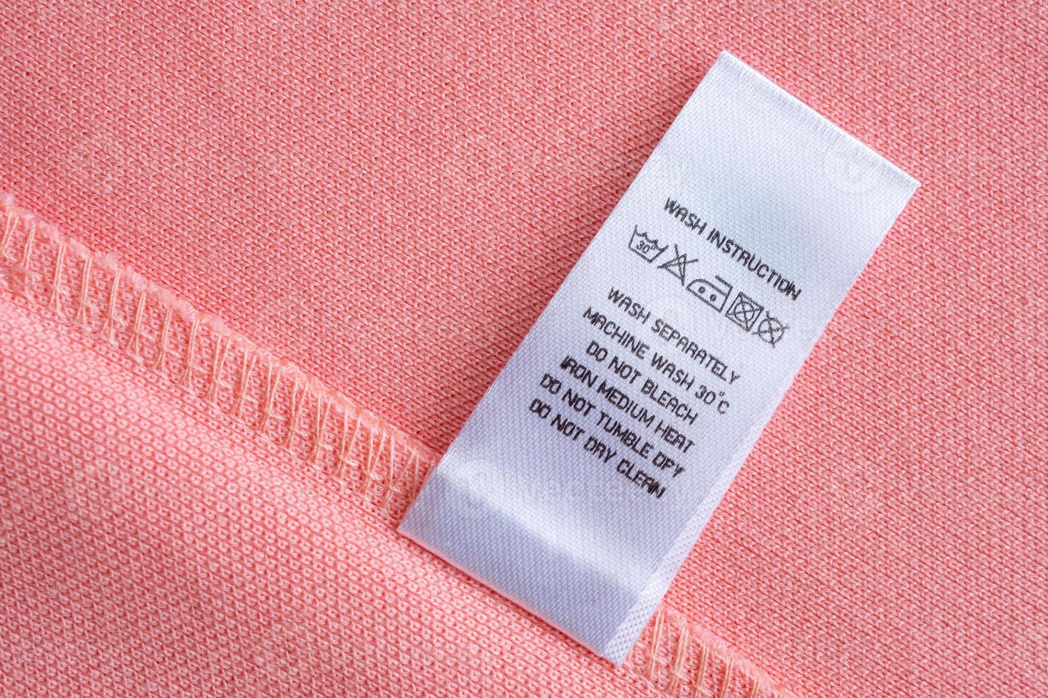 White laundry care washing instructions clothes label on pink cotton shirt photo