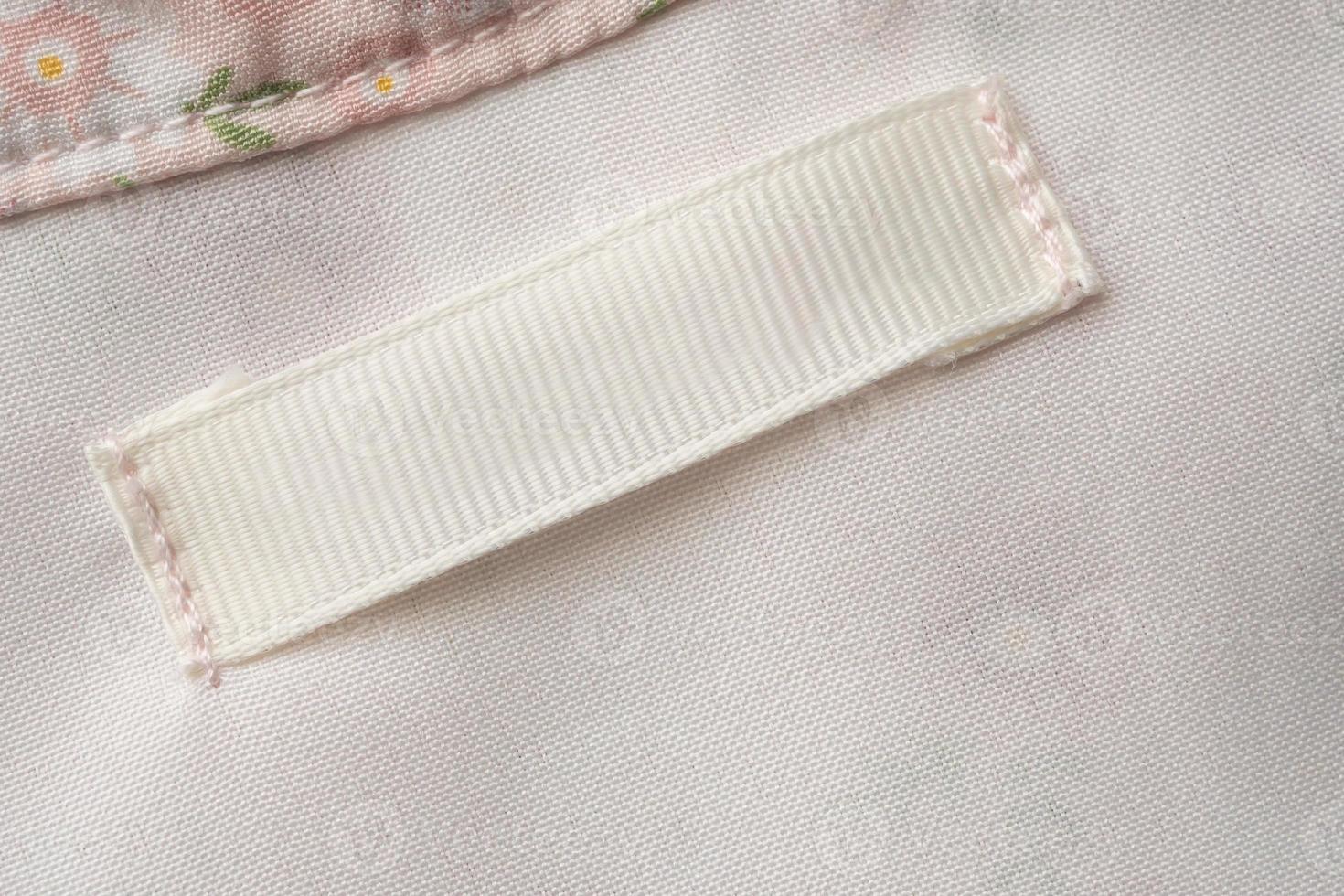 Blank laundry care clothes label on fabric texture background photo