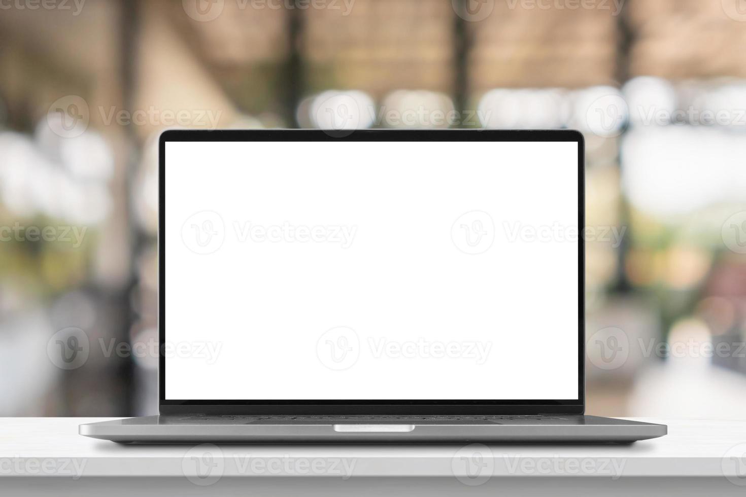 Laptop with blank screen on marble table with cafe coffee shop blur background photo