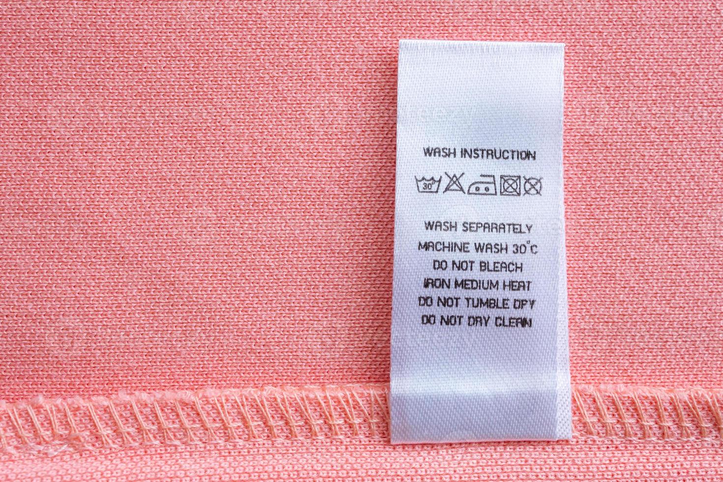 White laundry care washing instructions clothes label on pink cotton shirt photo