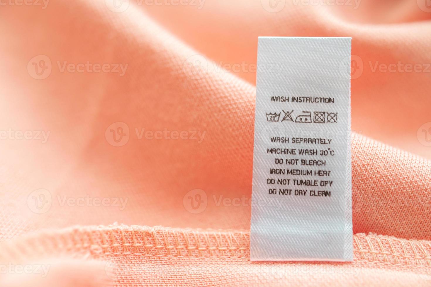 White laundry care washing instructions clothes label on pink cotton shirt photo