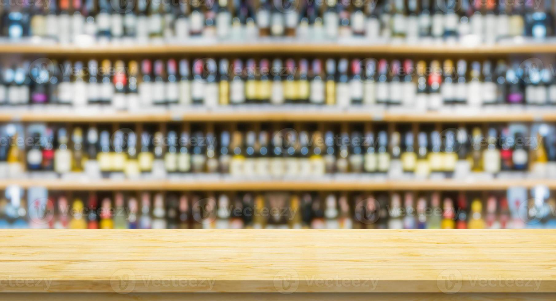 Empty wood table top with blur wine bottles on liquor alcohol shelves in supermarket wine store background photo