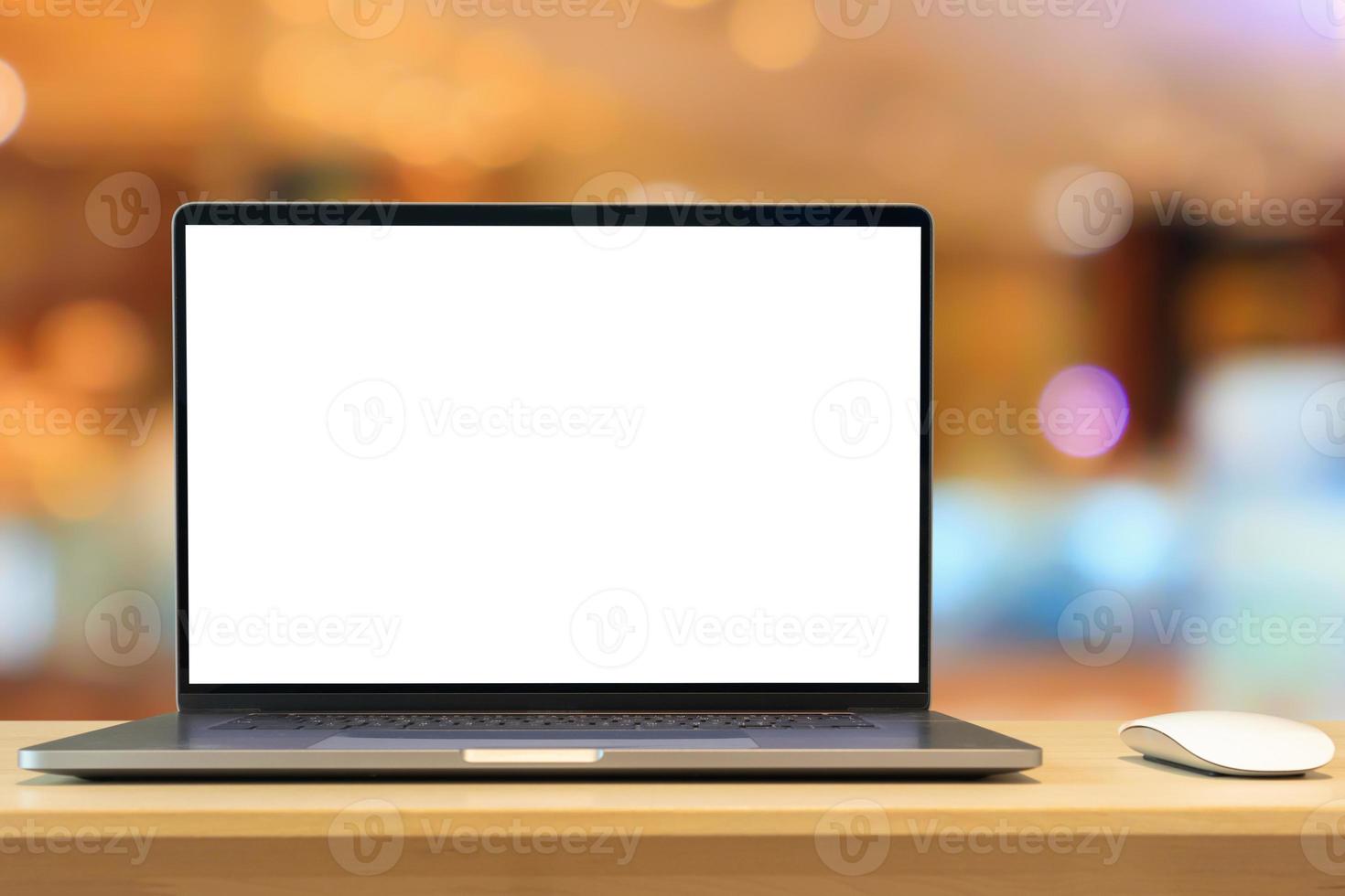 Laptop with blank screen on wood table with cafe coffee shop blur background photo
