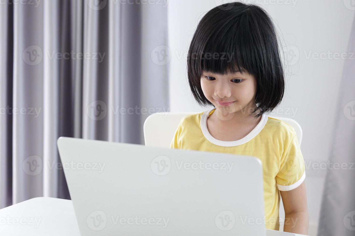 little asian girl student study online using laptop computer at home photo