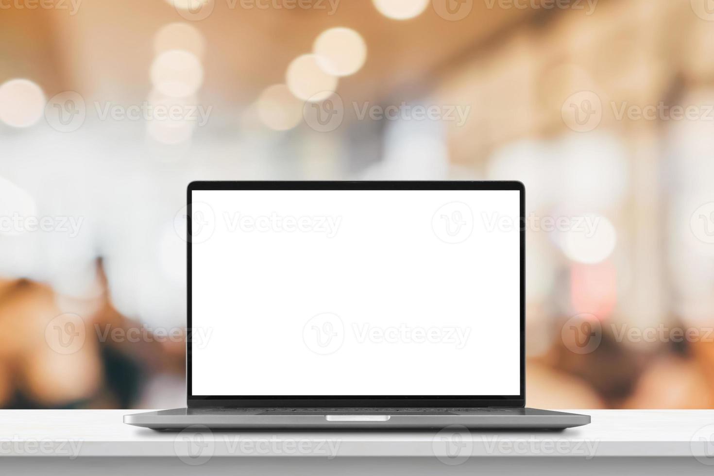 Laptop with blank screen on marble table with cafe coffee shop blur background photo