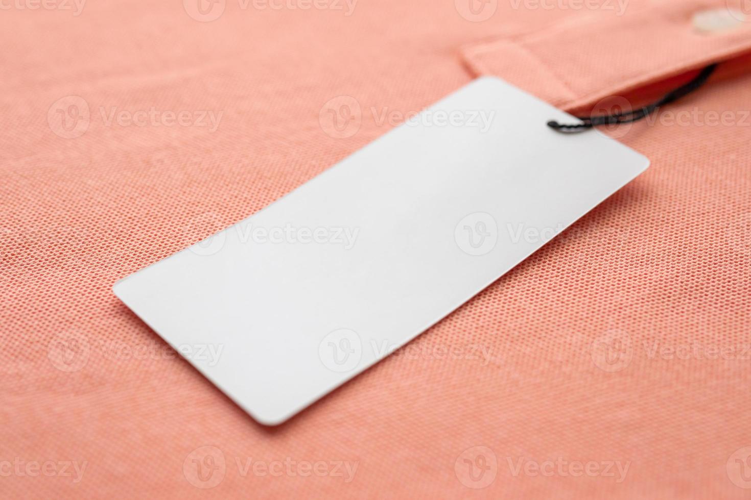 Blank white clothes tag label on pink fabric texture background photo