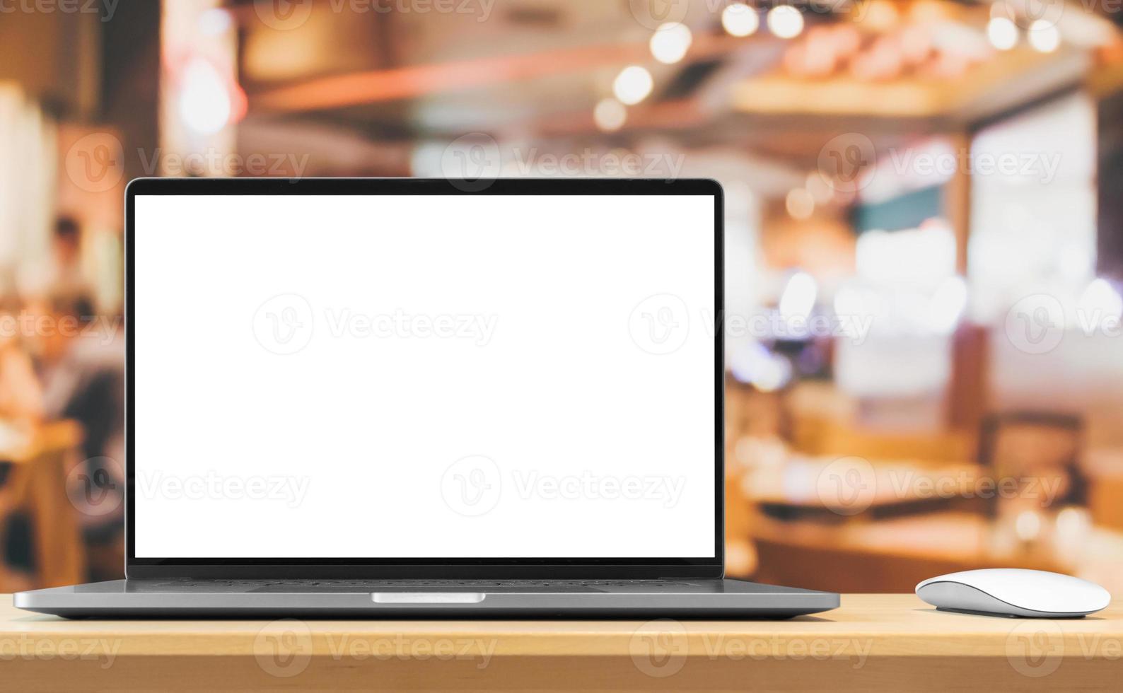 Laptop with blank screen on wood table with cafe coffee shop blur background photo