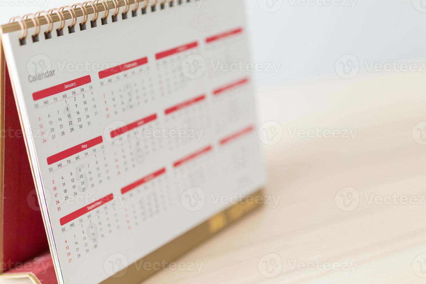 Calendar page close up on wood table with white wall background business planning appointment meeting concept photo