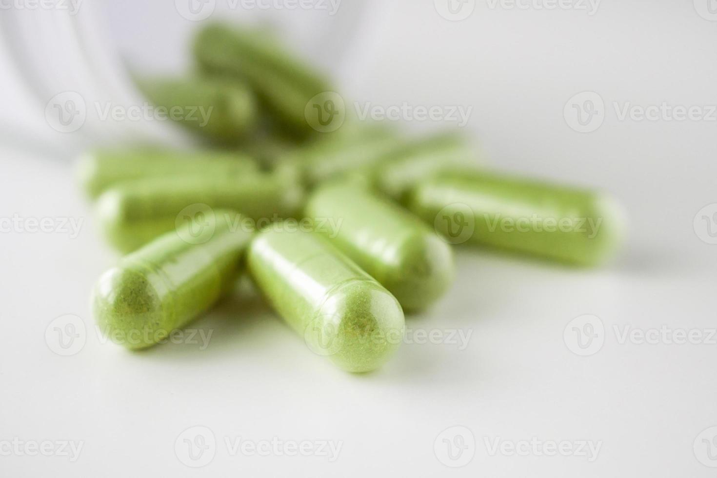 Herbal medicine capsules with bottle on white background photo