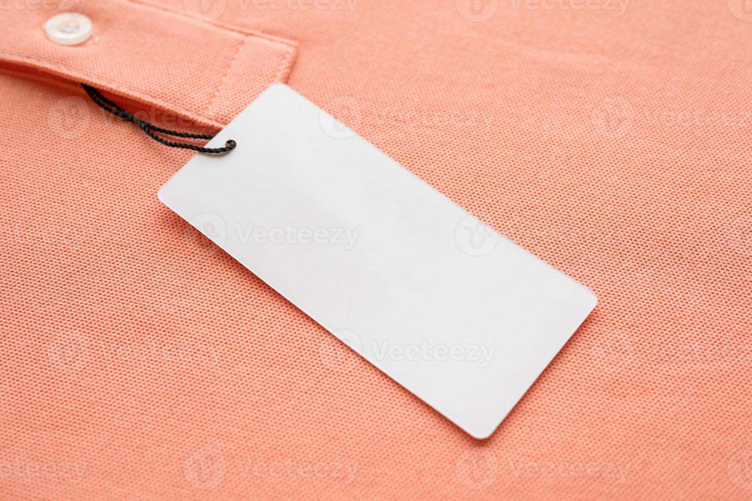 Blank white clothes tag label on pink fabric texture background photo