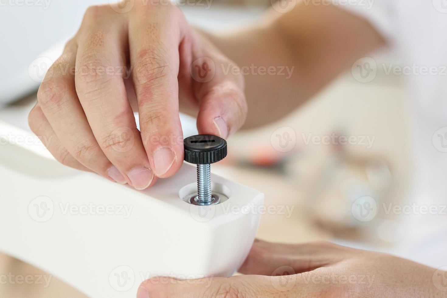 Asian man assembling furniture at home with adjustable table leg photo