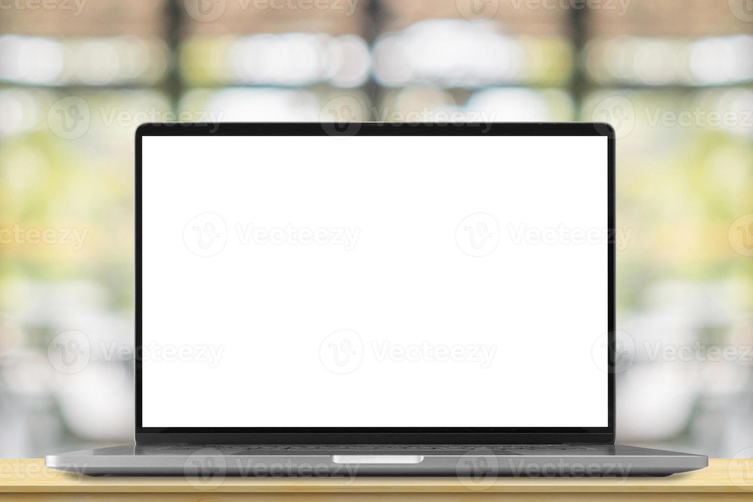 Laptop with blank screen on wood table with cafe coffee shop blur background photo