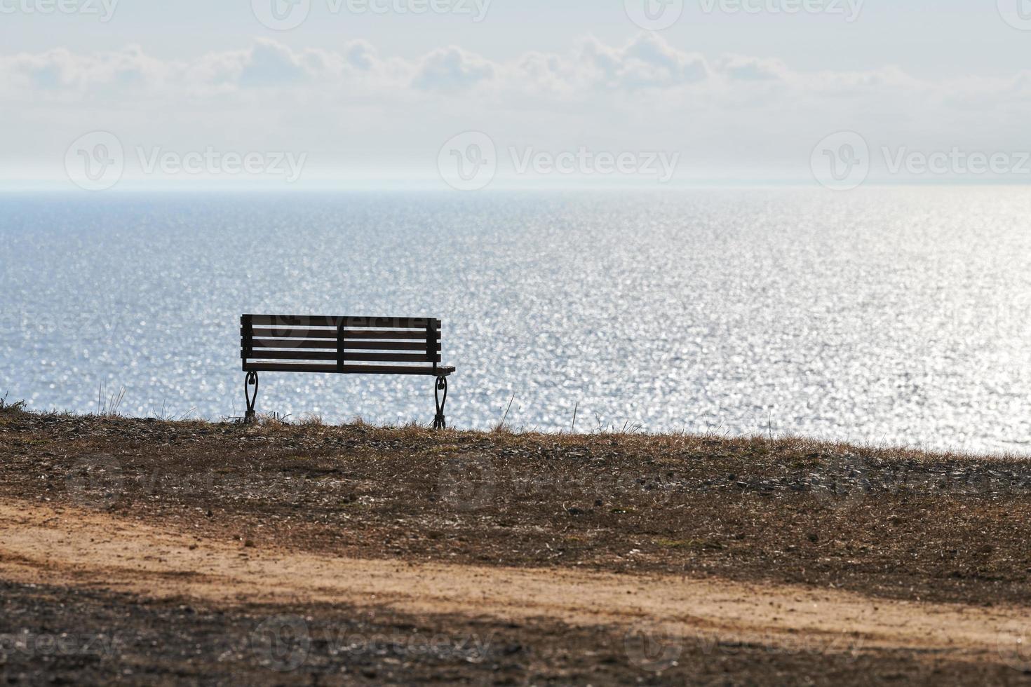 Empty bench on cliff before sea background, peaceful and quiet place for thinking alone photo