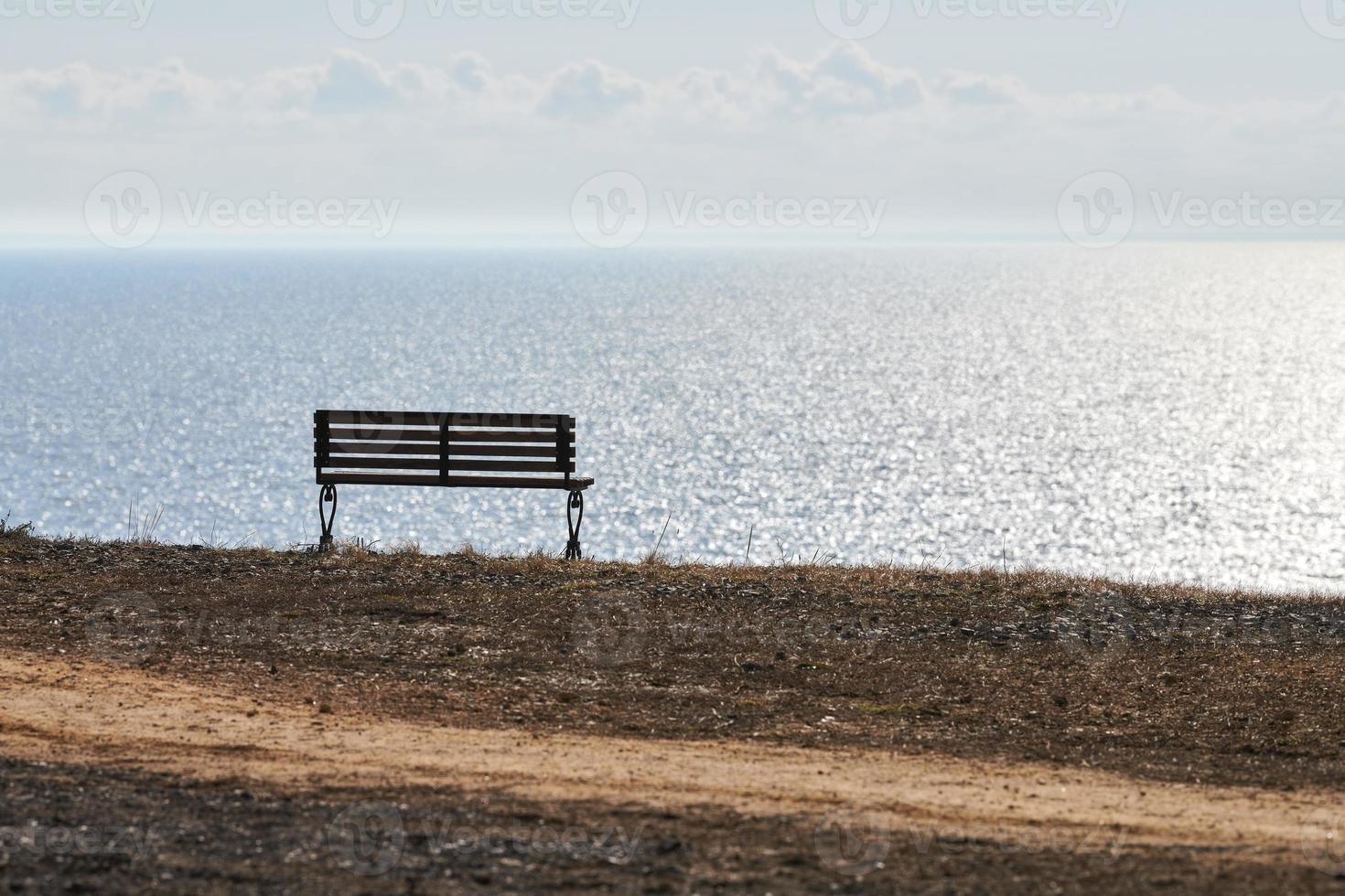 banco vacío en el acantilado antes del fondo del mar, lugar tranquilo y silencioso para pensar solo foto