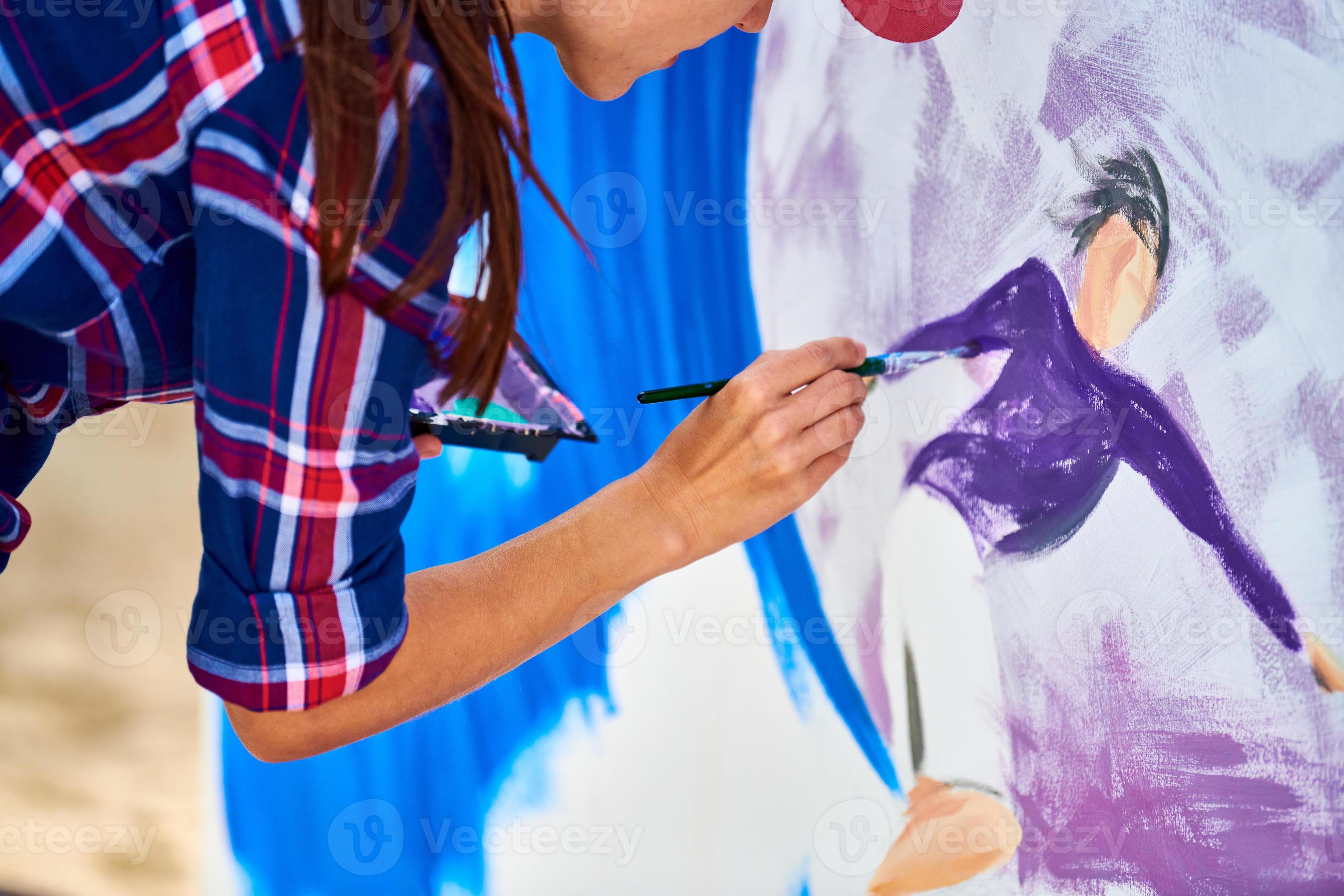 Female artist painting on wooden canvas board, painting abstract colorful picture, outdoor