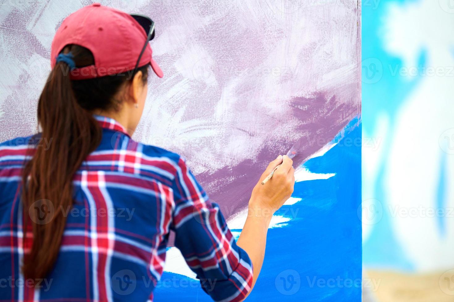 Female artist painting on wooden canvas board, painting abstract colorful picture, outdoor festival photo