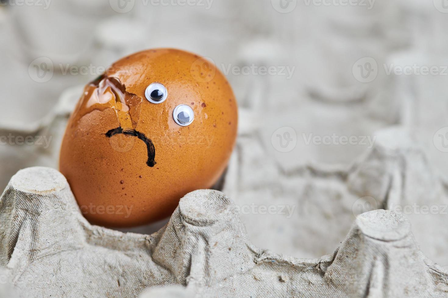 Sad cracked egg in paper egg tray photo