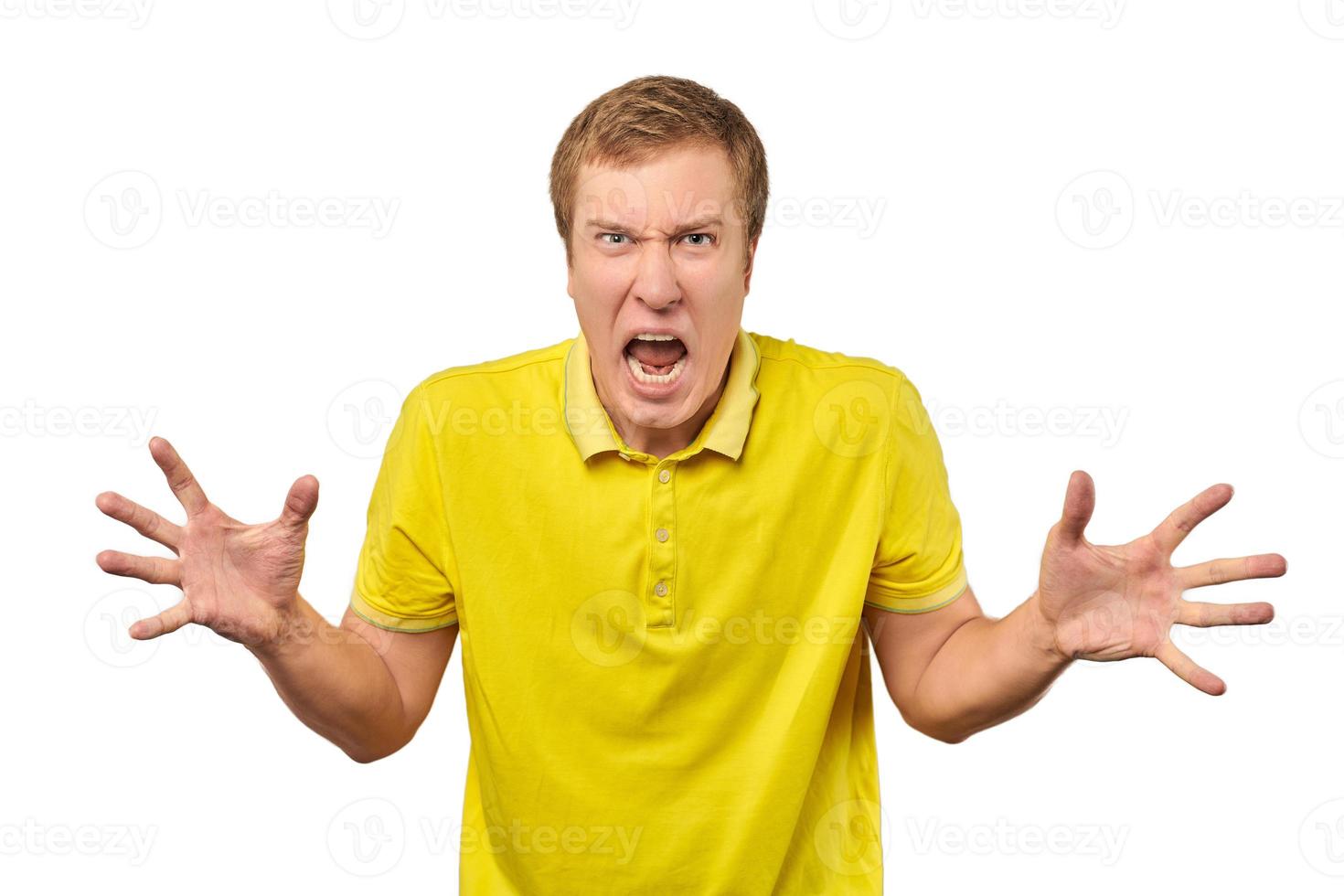 Angry young man in yellow T-shirt spread his hands and yelling isolated on white background photo