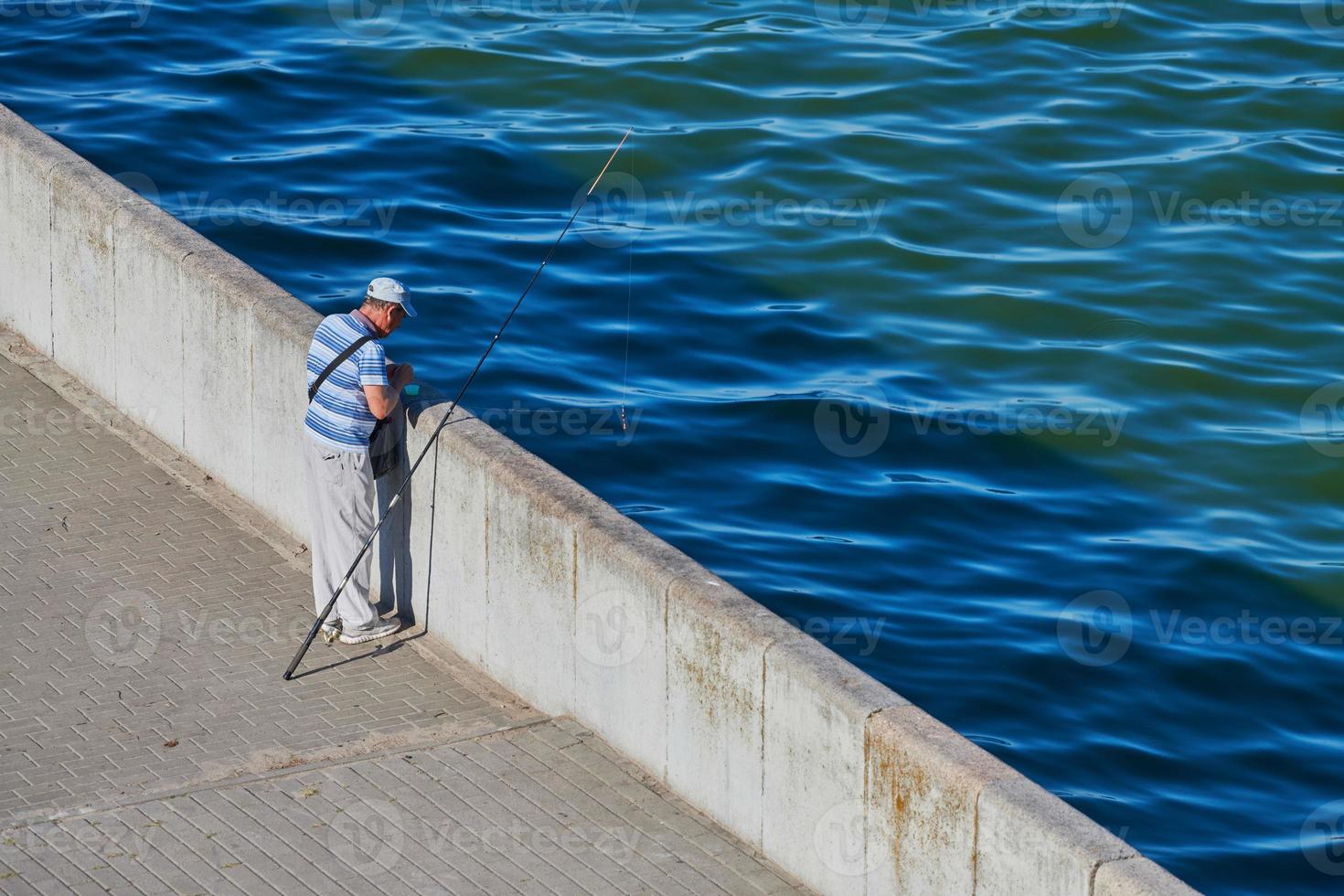 Old fisherman on waterfront photo