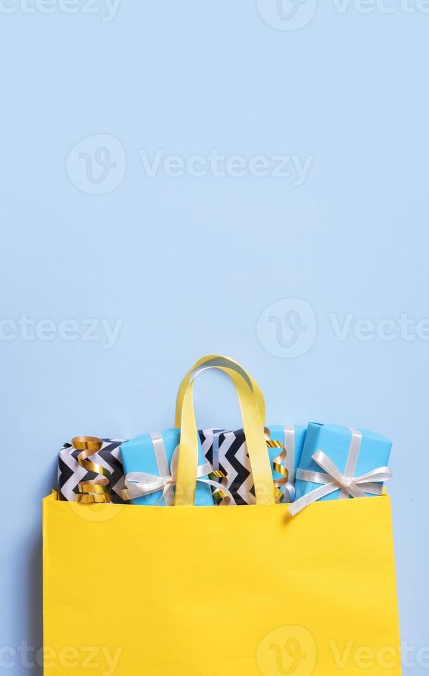Many gifts for the holidays concept. Holiday gift boxes with bows in a gift bag on a color background photo