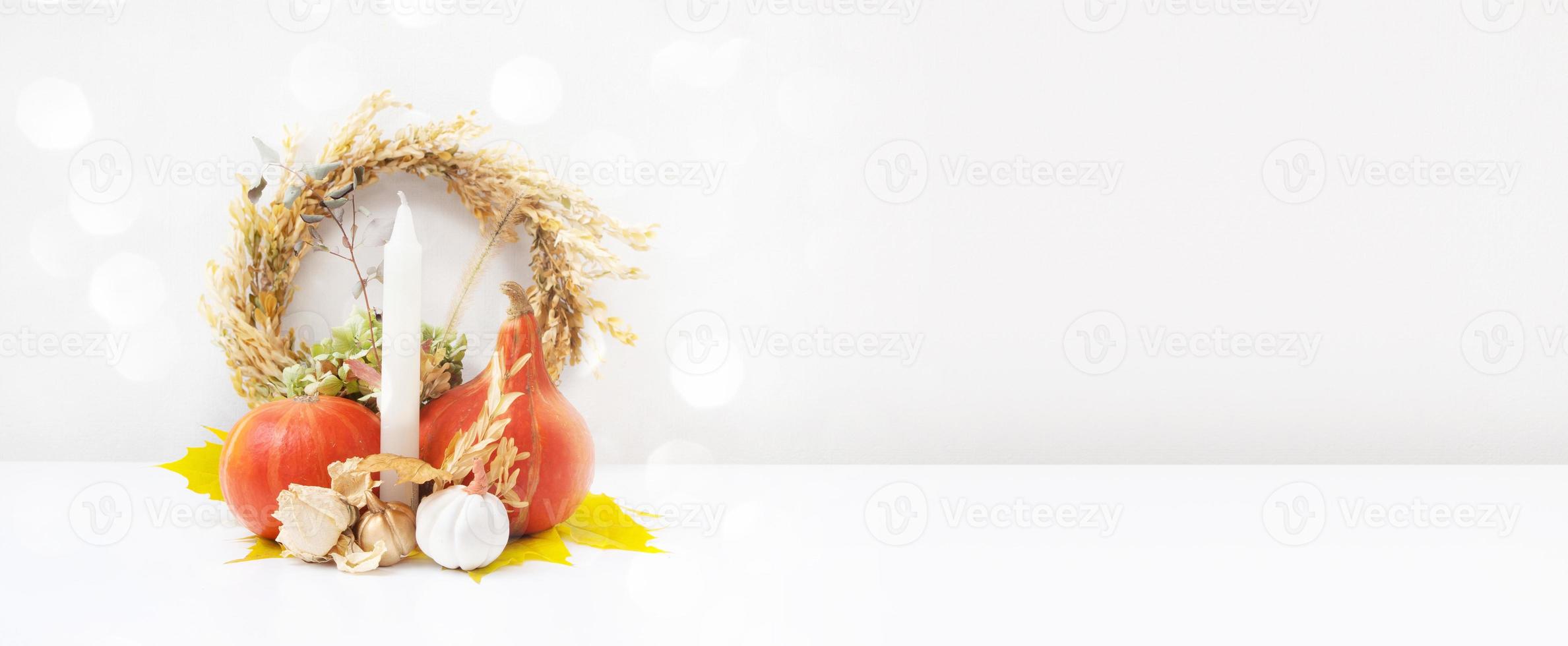 Autumn banner. Dried leaves wreath, pumpkins and candle on white background. Autumn fall and thanksgiving day concept. Still life photo