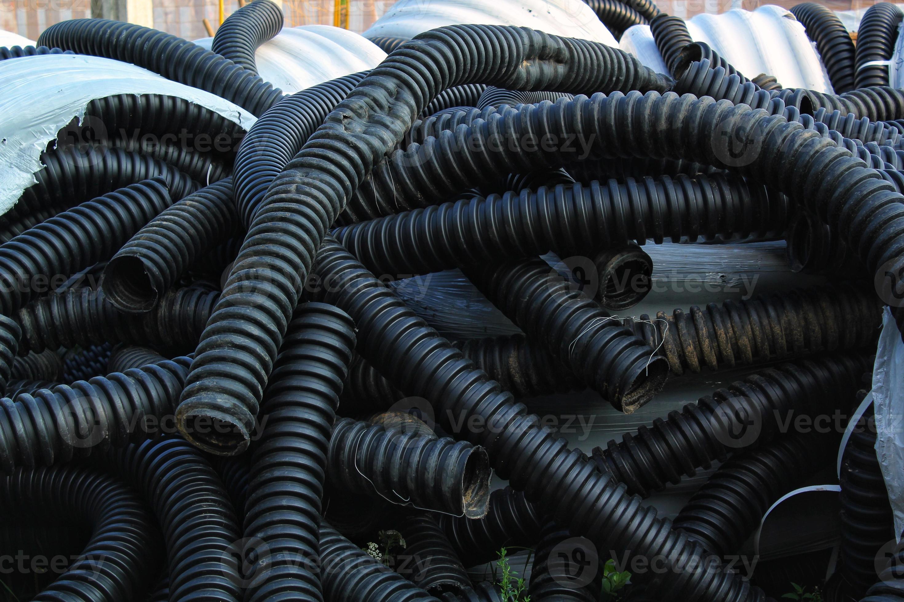 Rolled up pile of twisted, high pressure flexible black rubber pvc
