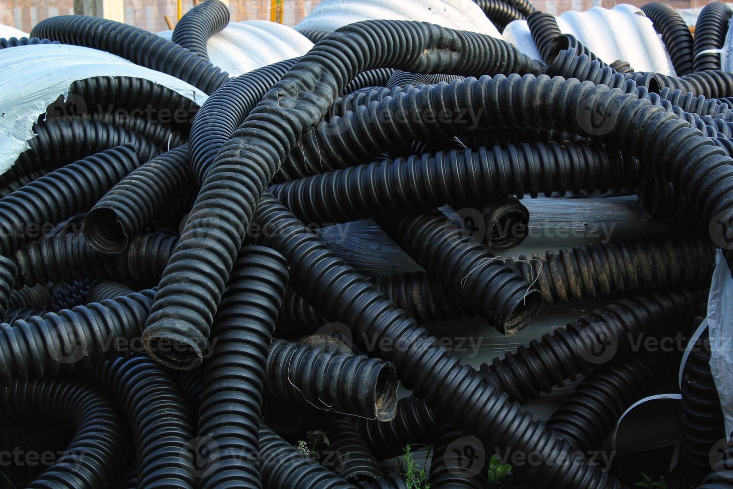 Rolled up pile of twisted, high pressure flexible black rubber pvc