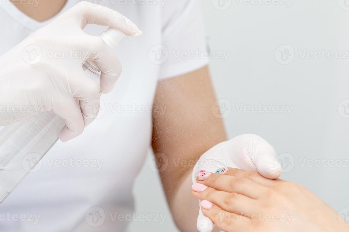 Manicurist is appies spray on client hand. photo