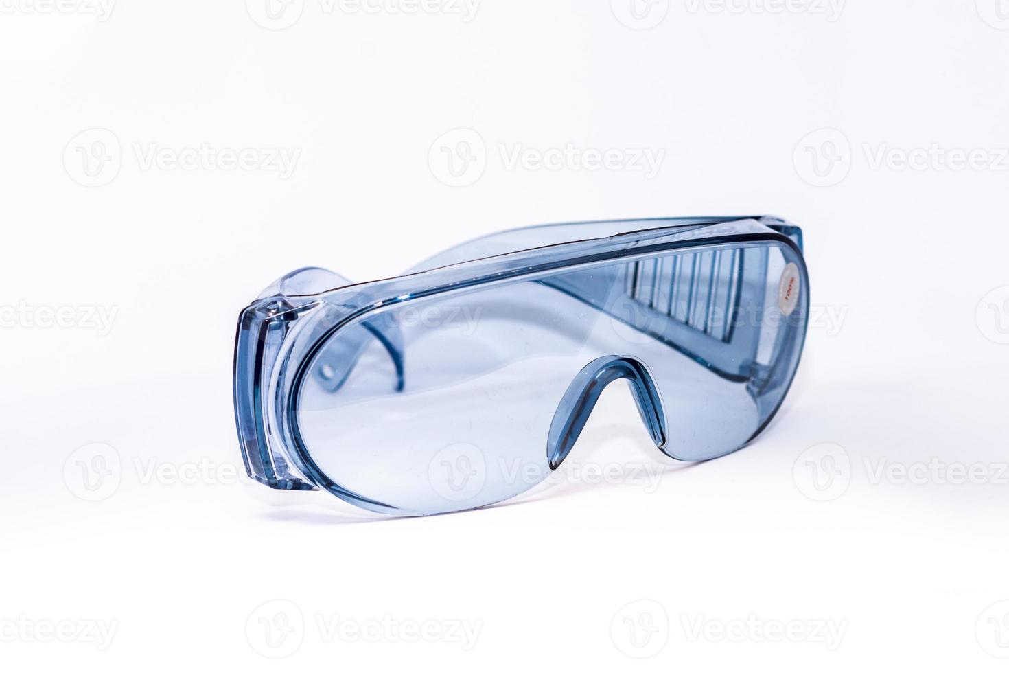 Blue plastic safety glasses on a white background isolated, close -up. Concept of occupational health and safety photo