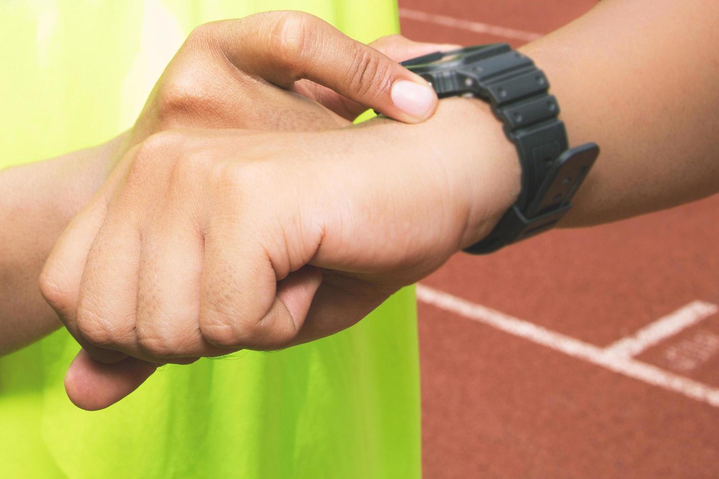 atleta revisando su reloj de pulsera temporizador de carrera corriendo listo en el campo de práctica al aire libre. foto