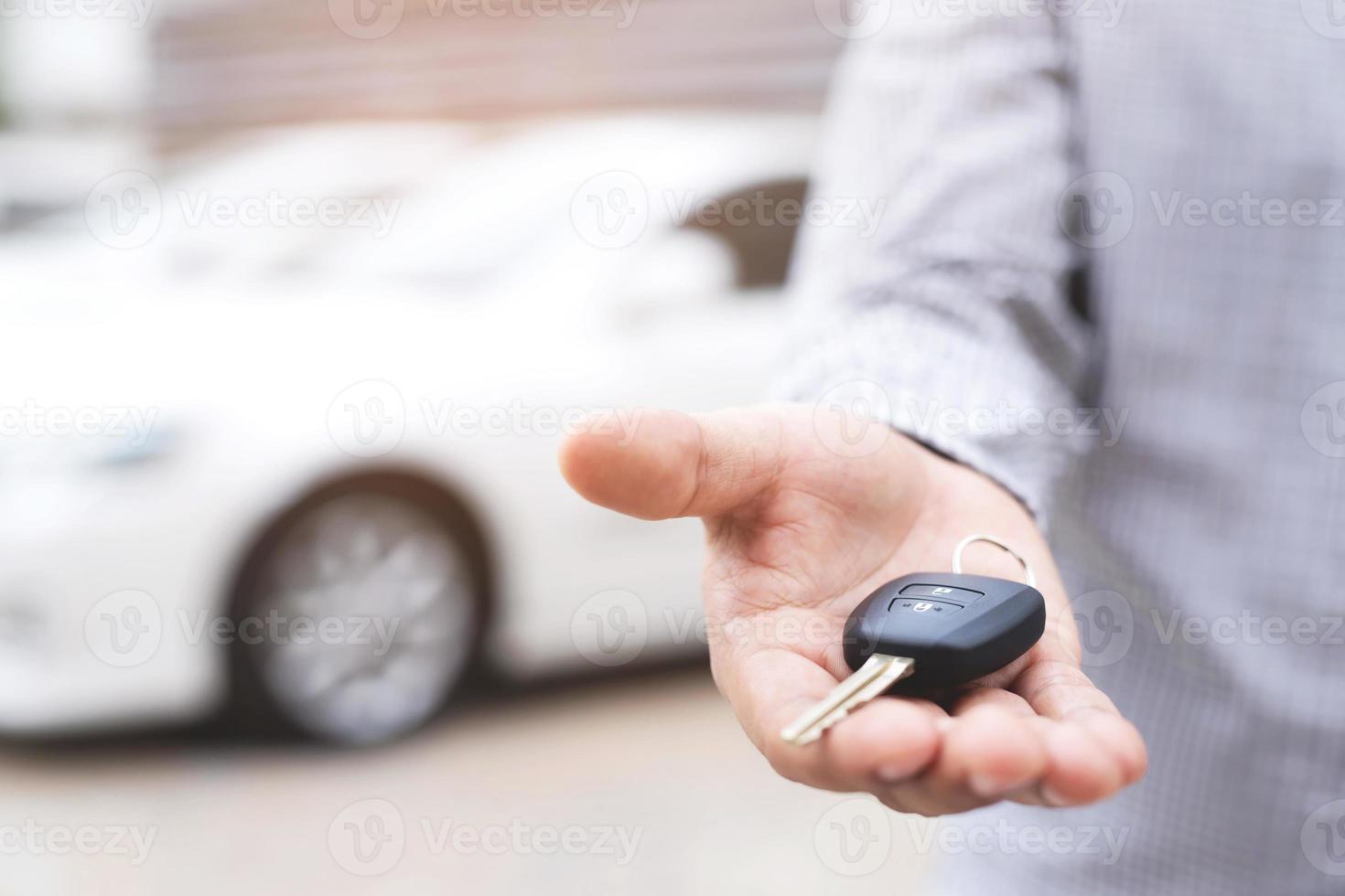 el vendedor está entregando las llaves del auto nuevo al cliente en la sala de exposición. foto