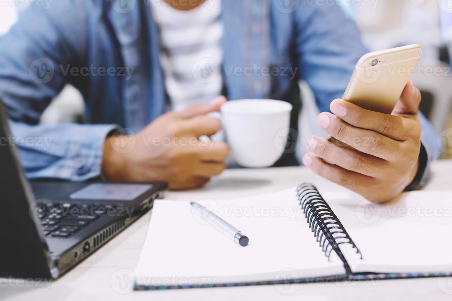 close up writer hand person people sit in coffee shop are writing notepad down write down the story into the book on table And use the phone to record sounds placed beside the coffee cup. photo