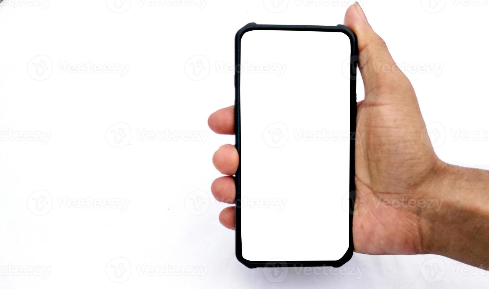 Man holding smartphone with blank screen on white background, closeup of hand. Space for text photo