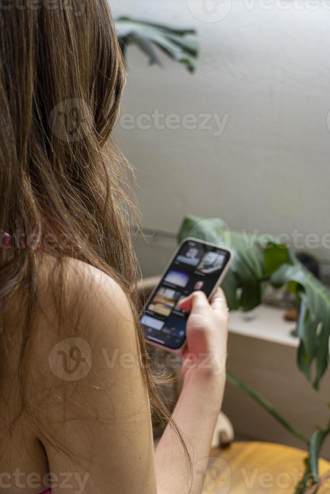 young hispanic woman, looking at her cell phone checking her social networks photo