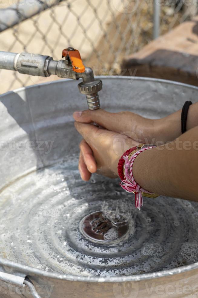 Awoman washing her hands outside, in a makeshift sink made of metal and pipes. mexico photo