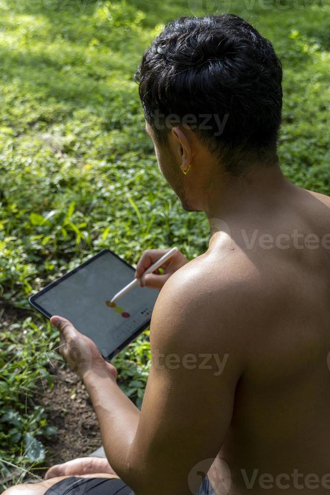 young man explaining drawing on his tablet, while teaching chakra, yoga and meditation class, mexico photo