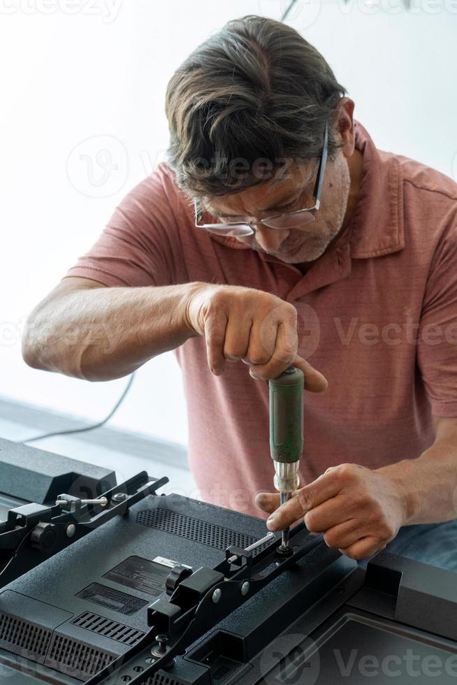 Mexican Latino man repairing a TV screen, checking for faults. photo