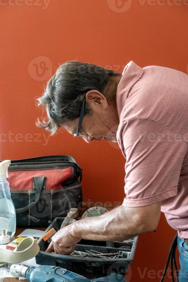 hombre latino buscando herramientas en su caja de herramientas, hispano, con destornillador en la mano foto