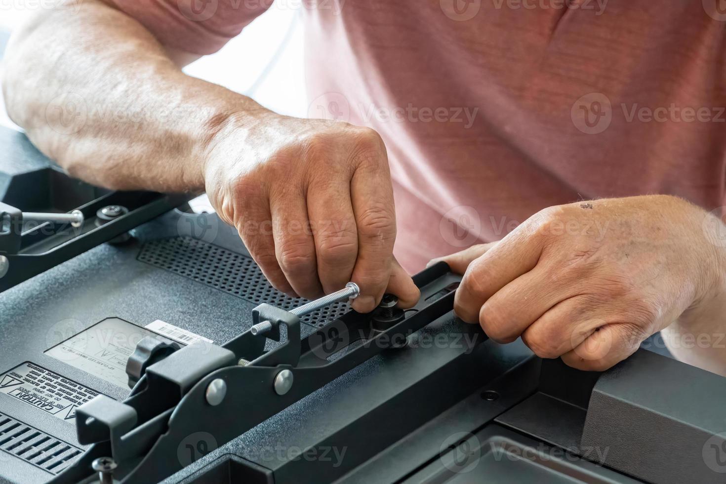 man installing the wall base for the television, it is a smart tv, adjusting with screwdriver photo